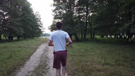 Young-Caucasian-male-running-in-forest-on-a-trail-in-summer