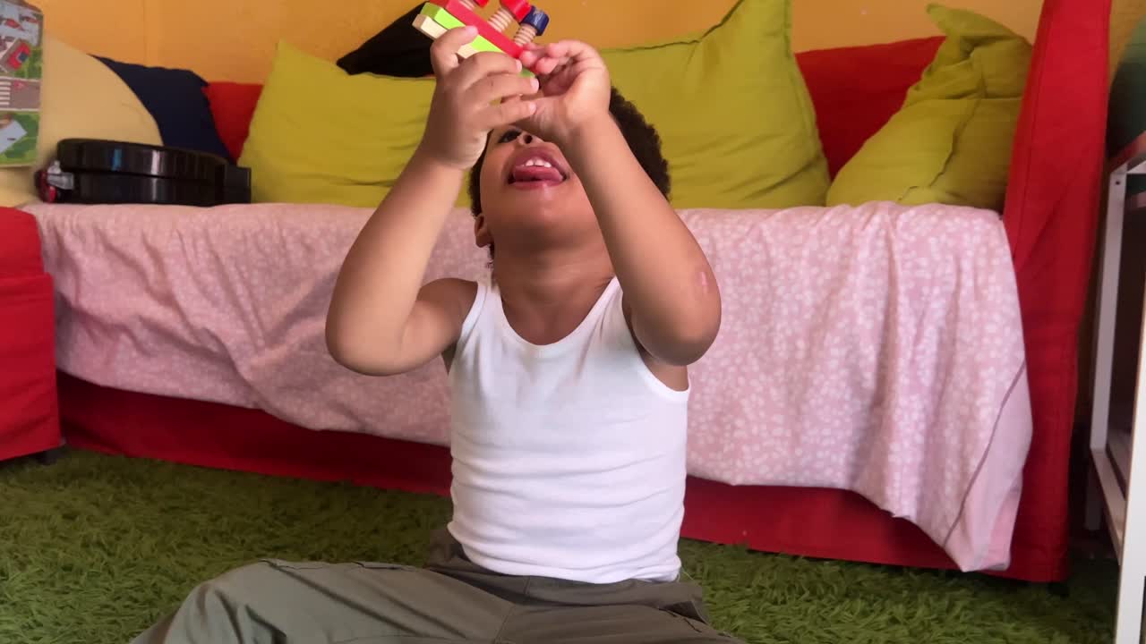 Joyful 3-year-old very expressive and exotic child playing with wooden tools and blocks at home