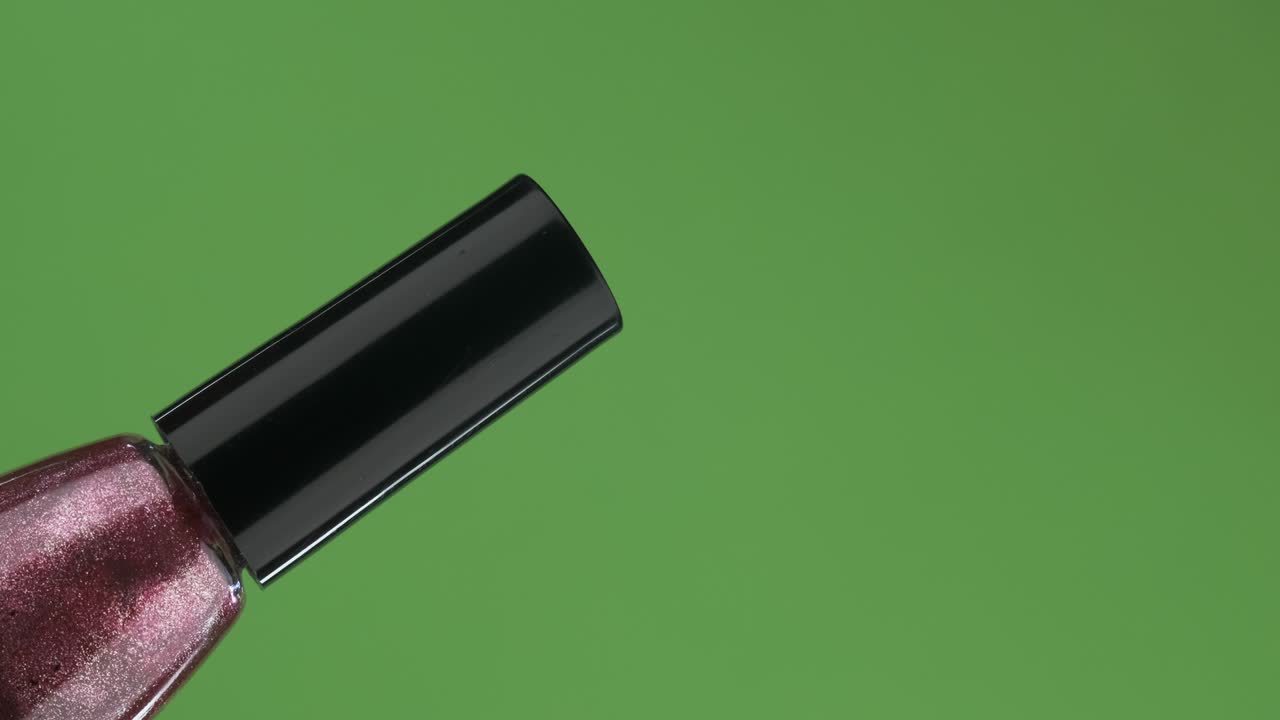 rotación diagonal de una botella de vidrio de esmalte de uñas. aislado en verde.