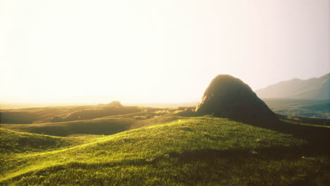 serene landscape with rolling hills and rocky outcrop under golden sunlight
