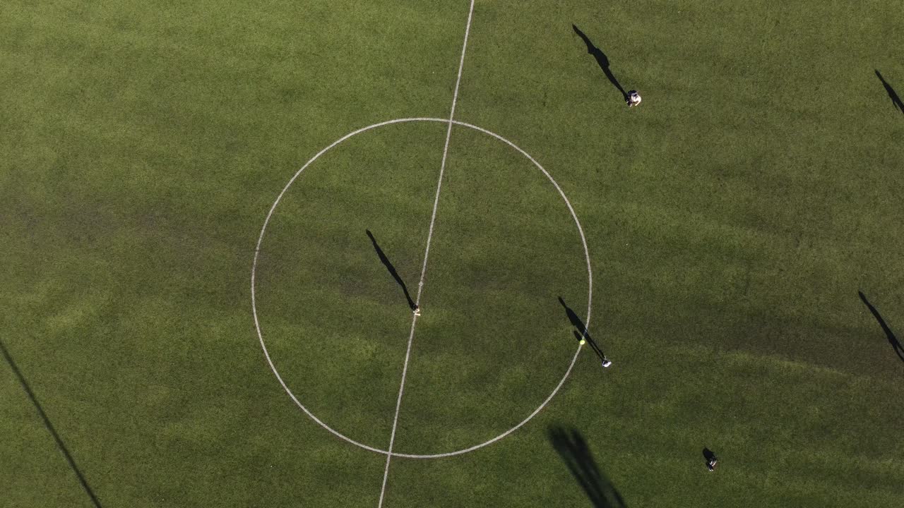 двое детей играют в футбол, отрабатывая пасы в центральном круге травяного поля