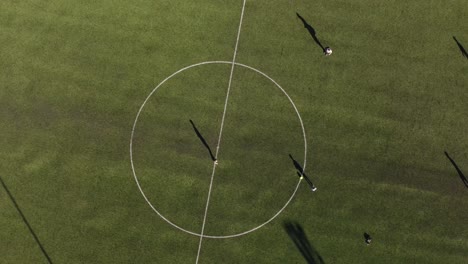 two kids playing football soccer practicing passes in central circle of grass field