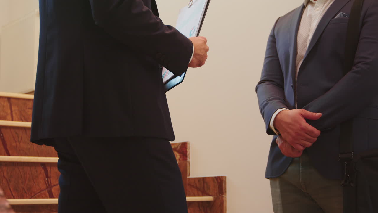 양복을 입은 두 명의 사업가들이 손을 흔들고 있습니다.