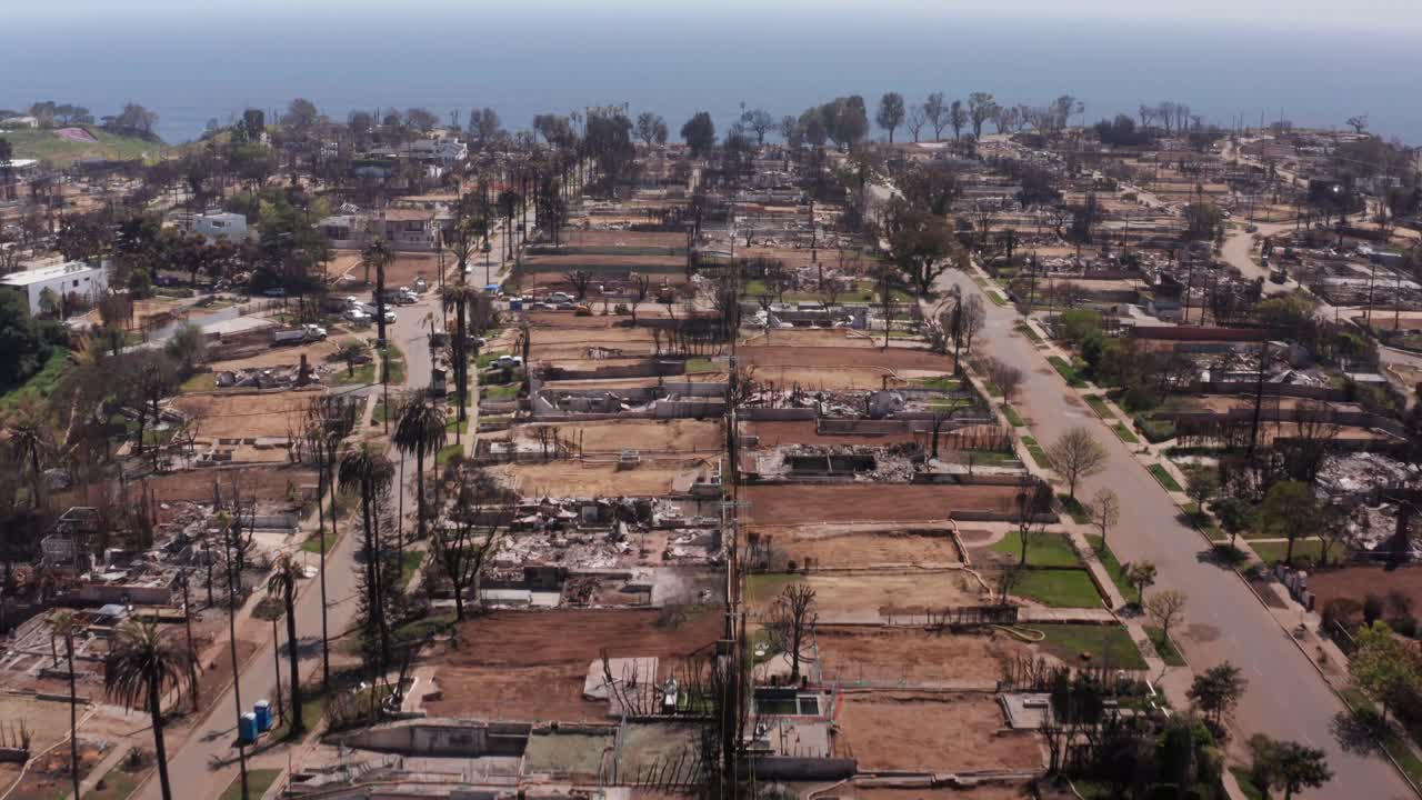 Low aerial shot tilting up to reveal fire debris in a residential neighborhood after the Palisades Fire in Los Angeles, California. 4K