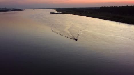 small motorboat traveling across the paraguay river at sunset