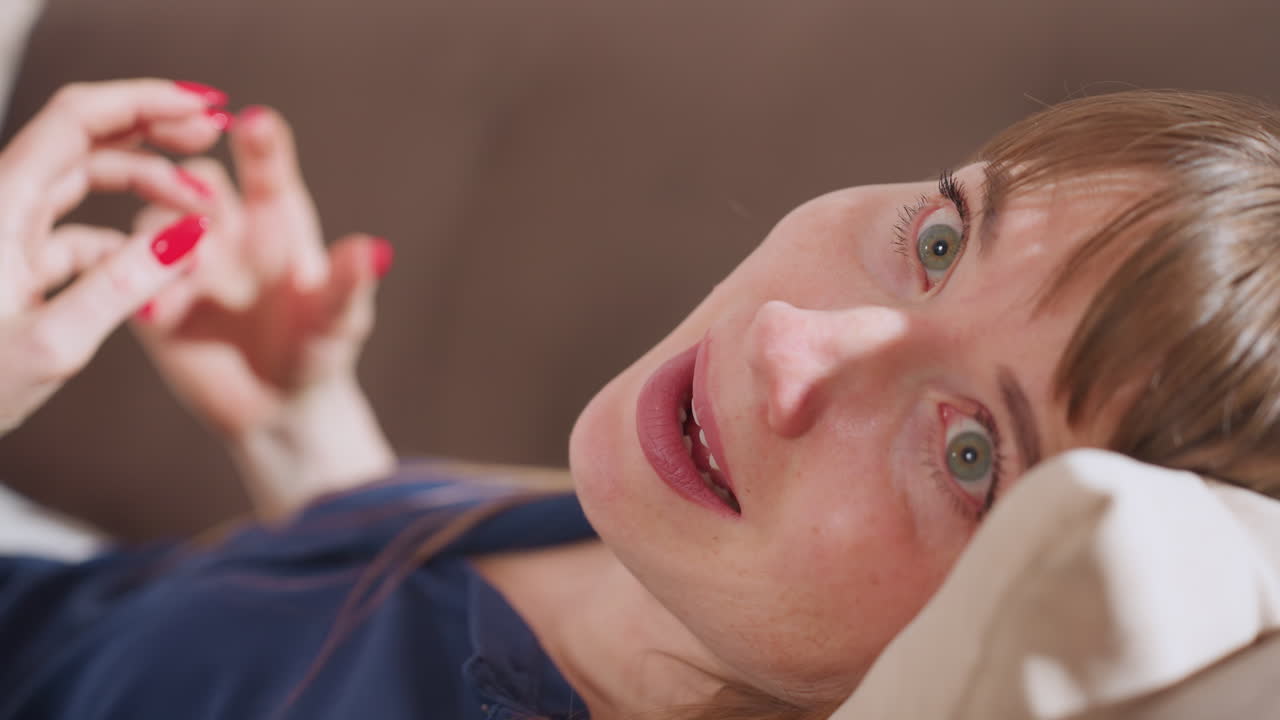 Close up view of recipient of care lying on sofa, turning head slightly while speaking during therapy, maintaining gentle eye contact and emotional expression in calm and supportive environment