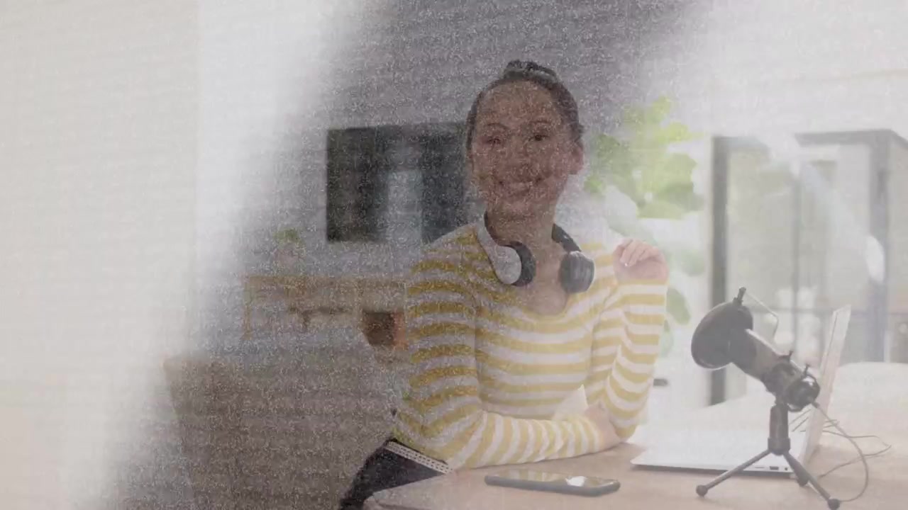 Woman picking up headphones and prepping microphone, adjusting tablet while preparing podcast