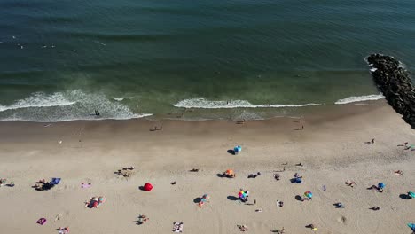 Una-Vista-De-Pájaro-Sobre-La-Gente-Que-Se-Relaja-En-La-Playa-En-Un-Día-Soleado