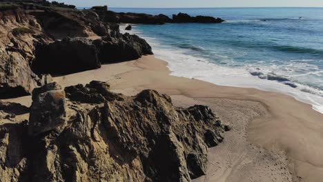 Waves-crashing-on-sunny-rocky-coastal-beach-during-late-afternoon