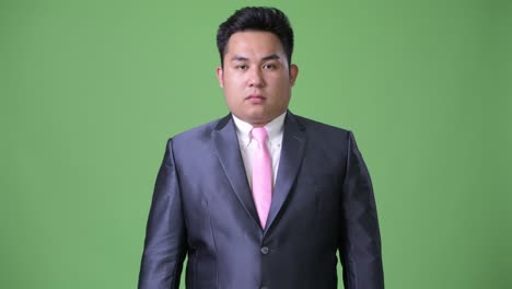 초록색 배경에 젊은 잘생긴 과체중 아시아 사업가