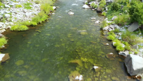 Aerial-flight-over-creek,-shallow-river-rapids-at-24-frames-per-second