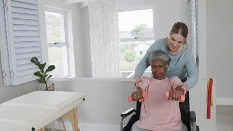 caucasian female physiotherapist,senior african american woman in wheelchair exercising, slow motion