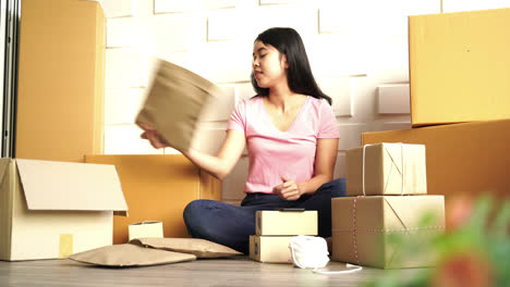 propietaria de una empresa asiática que trabaja en casa con una caja de embalaje en el lugar de trabajo