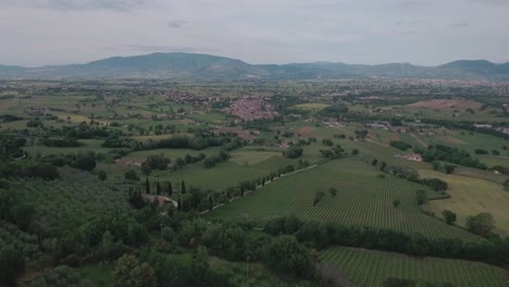aerial drone shot flying towards medieval town over italian countryside in umbria, italy