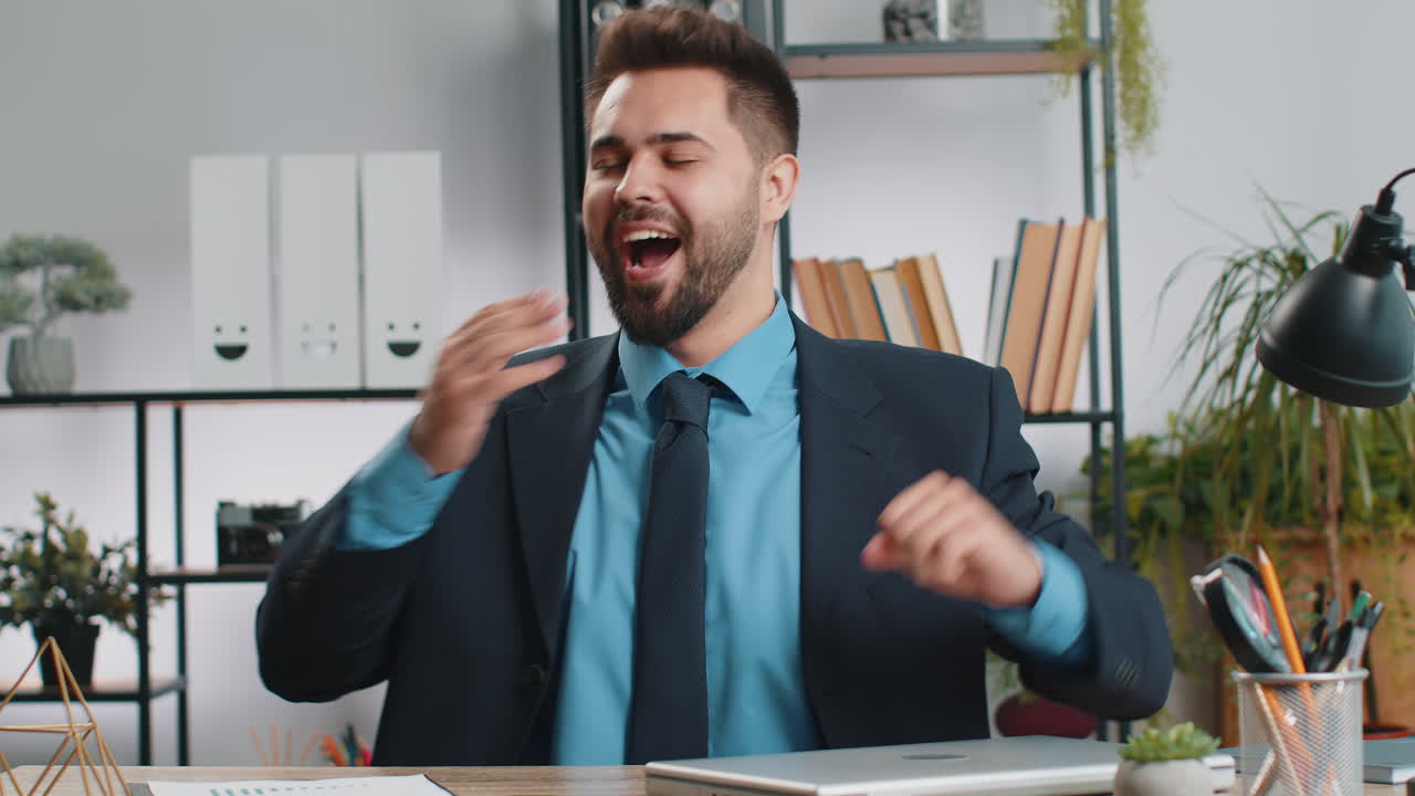 Uomo d'affari caucasico seduto alla scrivania dell'ufficio, chiude il laptop dopo aver terminato il lavoro da remoto