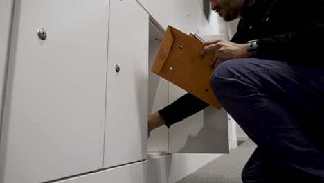 low angle view of person in casual wear opening locker in a modern, bright interior, indirect lighting