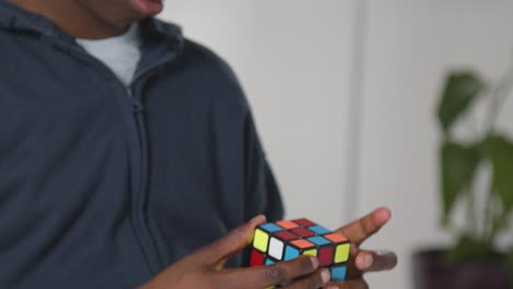 studio shot of boy on asd spectrum solving puzzle cube wearing ear defenders 4