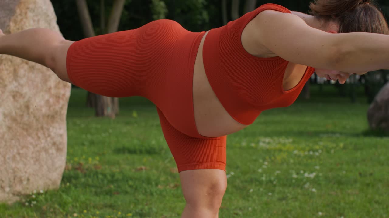 mujer embarazada haciendo postura de yoga en un parque