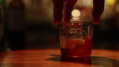 sequence of a hand stirring a drink with ice