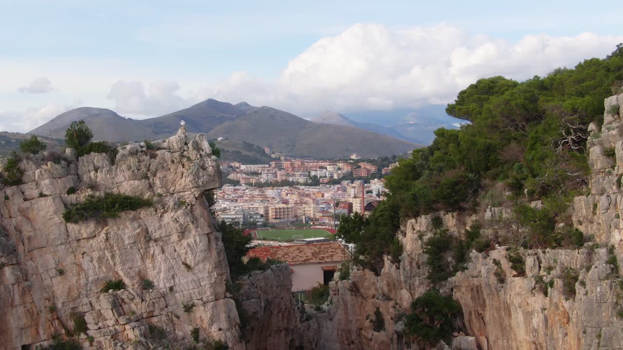 emocionante vuelo bajo dramático a través del promontorio montagna spaccata hacia la vista panorámica de la ciudad costera de gaeta y las cadenas montañosas, italia, enfoque aéreo superior