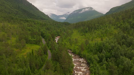 Aerial-View-Of-Road,-River,-Forest-And-Mountain-Range-In-West-Coast,-Norway