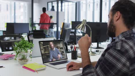 hombre de oriente medio teniendo una videollamada con un colega masculino en una computadora portátil en la oficina
