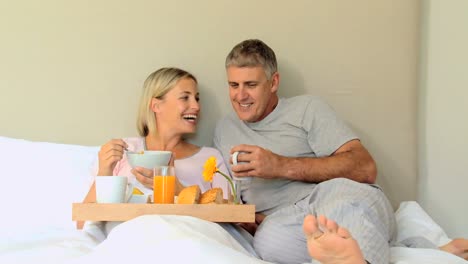 pareja disfrutando del desayuno en la cama