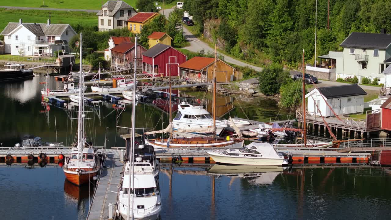 Beautiful sailboat and fishing boats docked at harbor or along pier in quaint fishing village in Norway