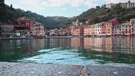 slider view over water of colorful pastel-colored houses on portofino waterfront