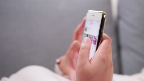 primer plano de las manos de una mujer joven usando y sosteniendo un teléfono inteligente, desplazándose hacia arriba y hacia abajo en la pantalla táctil, enviando un mensaje de texto