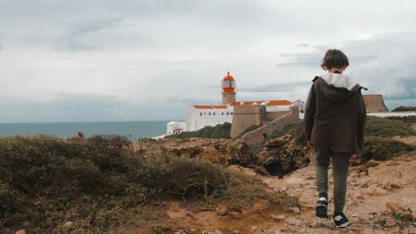 un niño turista en portugal tomando fotos del faro de cabo san vicente