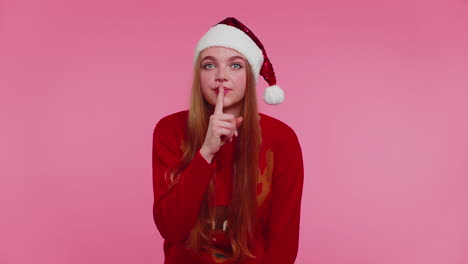 Woman-wears-red-Christmas-sweater-presses-index-finger-to-lips-makes-silence-gesture-sign,-secret