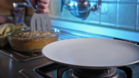 cutting home baked chicken and oatmeal dish using slotted turner in the kitchen to serve in a plate
