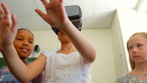 mixed race schoolgirl using virtual reality headset in classroom at school 4k