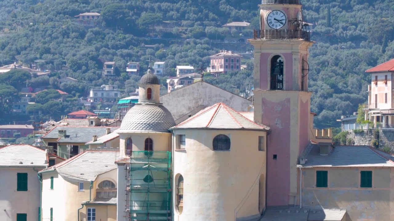 Una lenta inclinazione verso l'alto rivela una chiesa storica e una torre dell'orologio su uno sfondo collinare