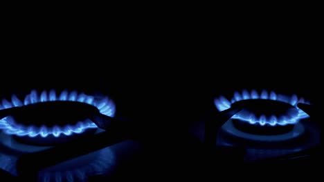 turn three on gas burners, blazing with blue flame, at night in kitchen. close