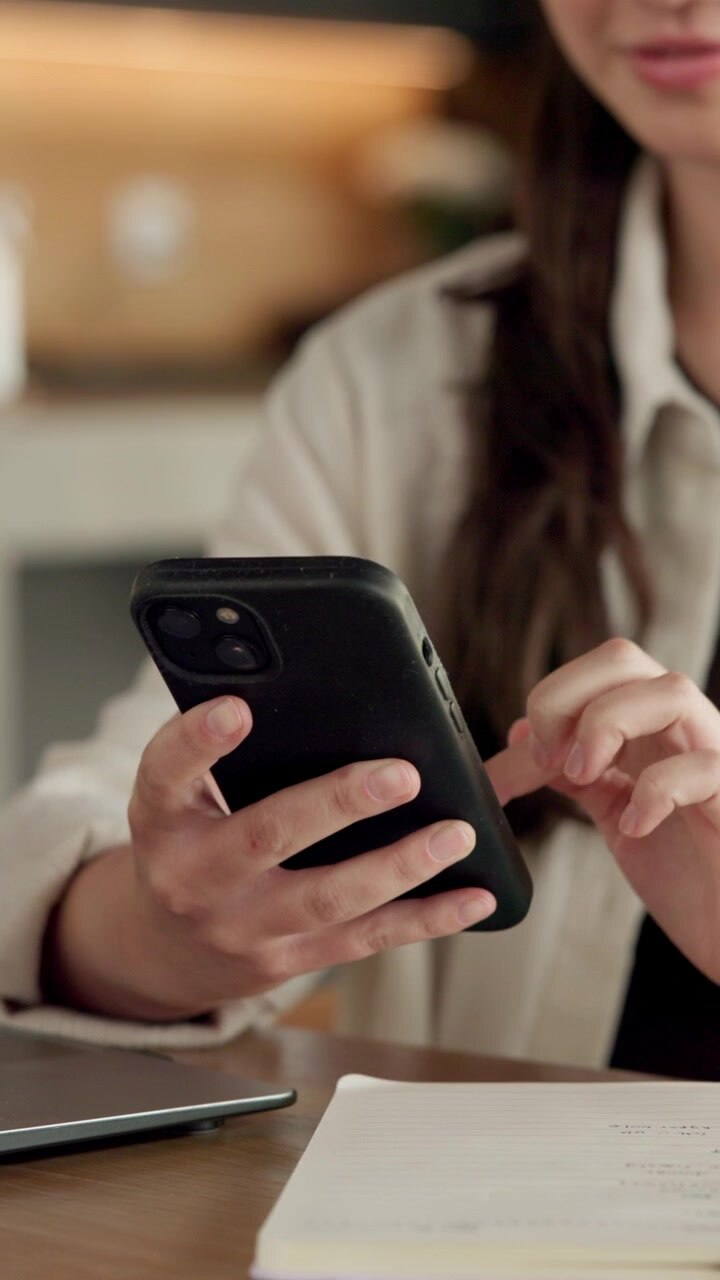 Donna che usa lo smartphone alla scrivania nell'ufficio di casa