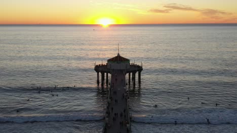 Turistas-Disfrutando-Del-Paisaje-De-La-Puesta-De-Sol-En-El-Muelle-De-La-Playa-De-Manhattan,-California---Estática-Aérea