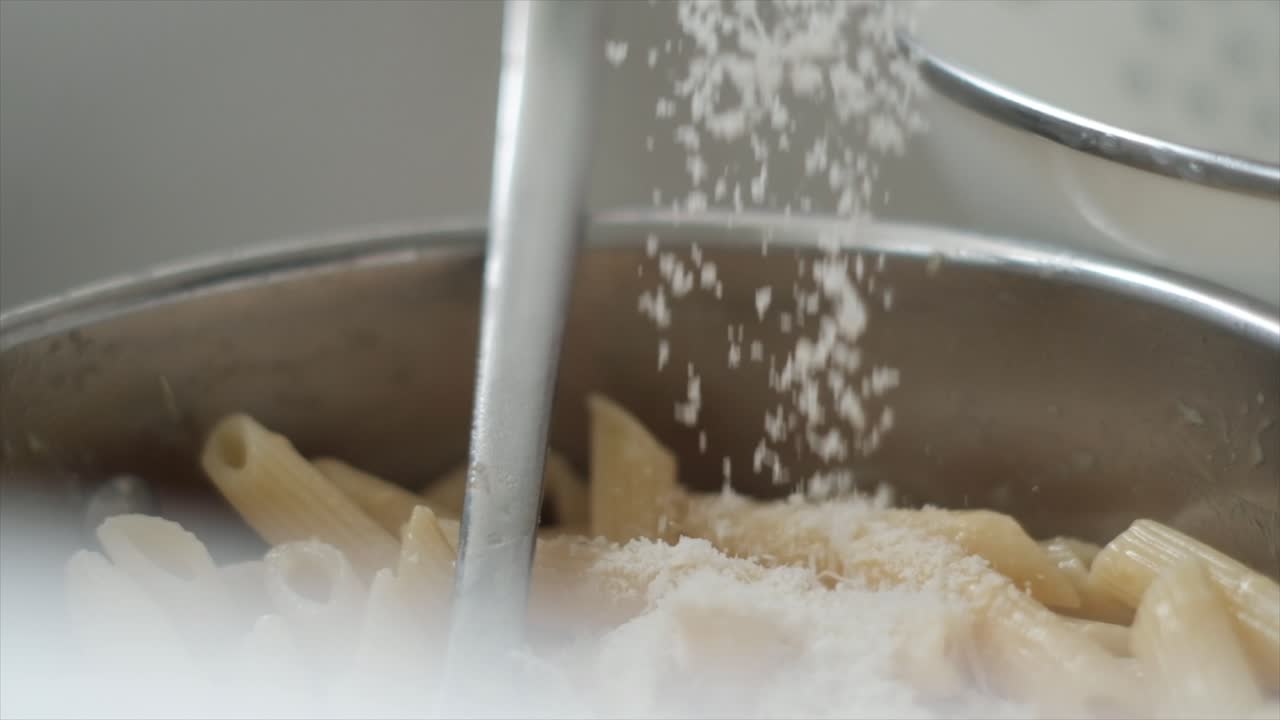 Parmesan Cheese Drizzling Over Penne Pasta in Slow Motion. The Real Carbonara. Gourmet Pasta Perfection. Slow-mo
