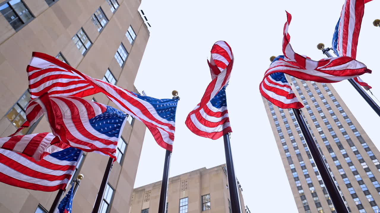 Pali con bandiere americane che sventolano nel vento. Angolazione dal basso. Simboli patriottici dell'America nelle strade di New York