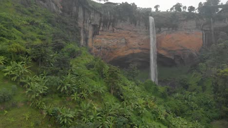 aerial shot rising up from the jungle floor and looking onto a large water fall plunging off a cliff in rural africa