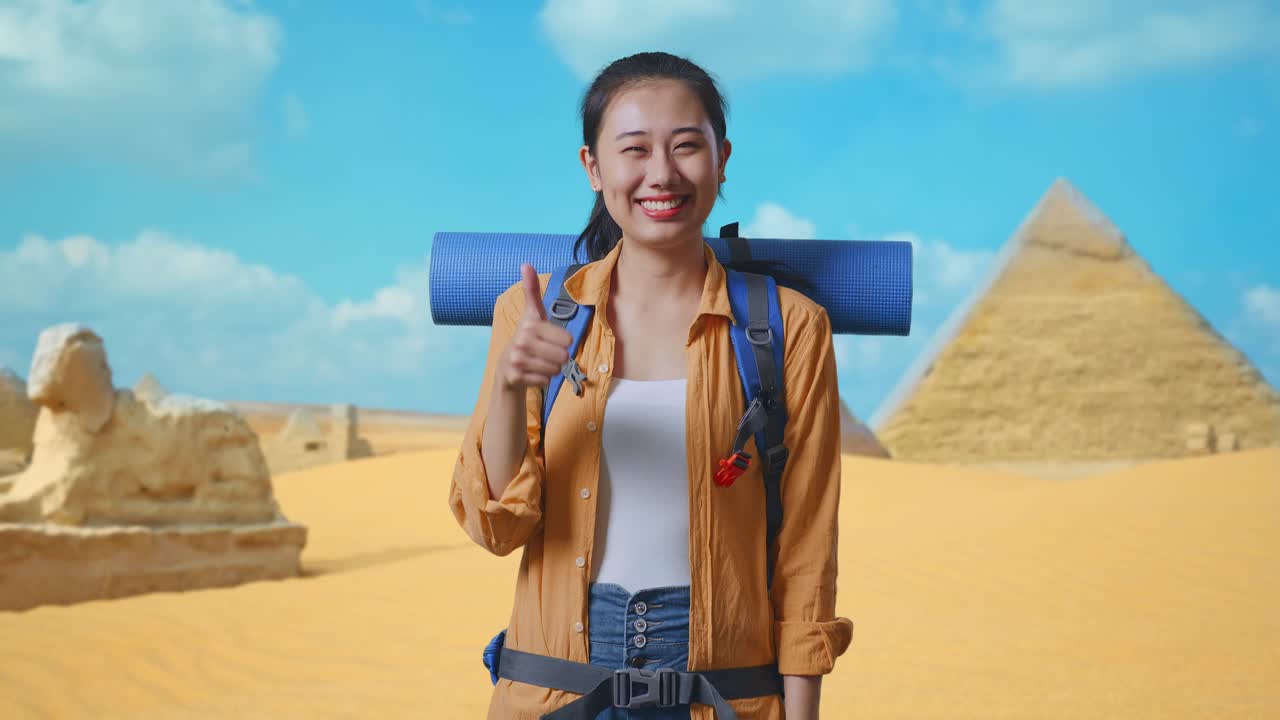 Asian Female Hiker With Mountaineering Backpack Smiling And Showing Thumbs Up Gesture To Camera While Traveling In Pyramid Of Giza