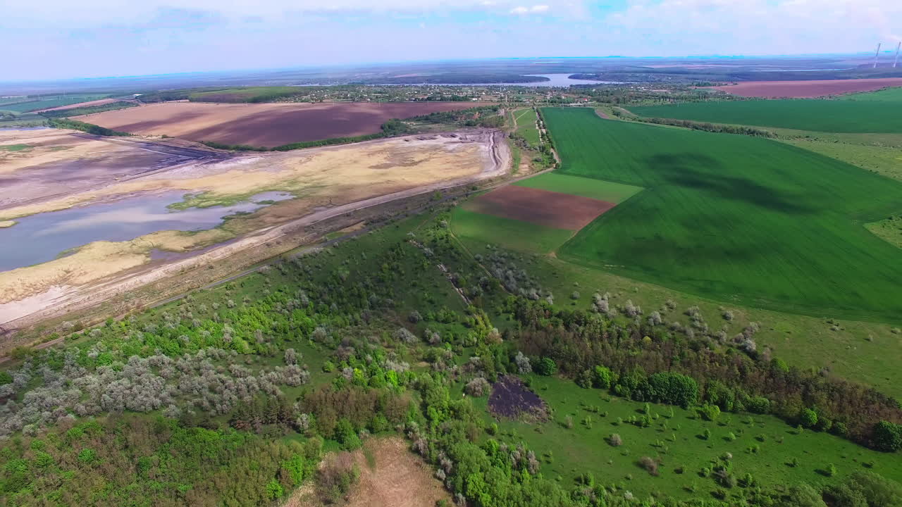 Beautiful diverse natural landscape outside of a big city. Clouds throwing shadows on the ground. View from top.