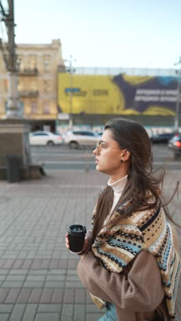 woman drinking coffee on city street