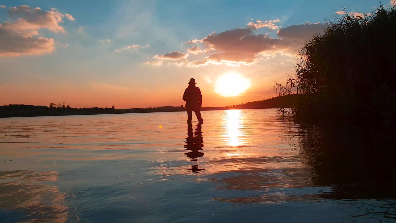 una niña atrapando un pez en un lago tranquilo con una impresionante puesta de sol en la distancia