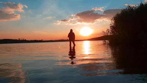 A-girl-catching-a-fish-in-a-calm-lake-with-a-stunning-sunset-in-the-distance