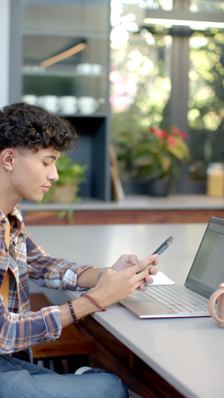 Vertical video: Young person using smartphone and laptop at home, engaging in conversation