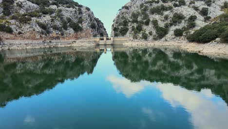 calm waters of gorg blau reflect the surrounding cliffs and greenery in mallorca. this serene location invites nature lovers to explore its natural beauty and tranquility.