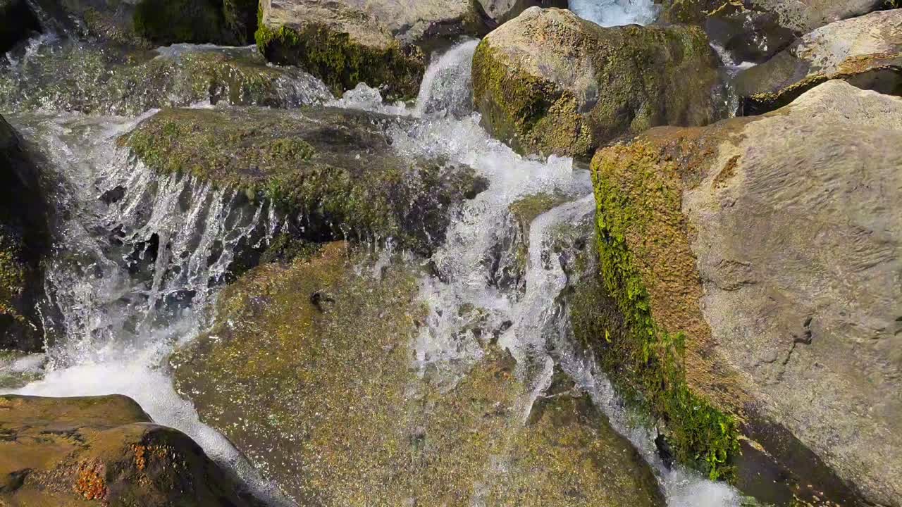 Static closeup shot of clear water flowing over rocks in a small mountain stream, cascading mini waterfalls at Weesen, Walensee, Glarus, Switzerland