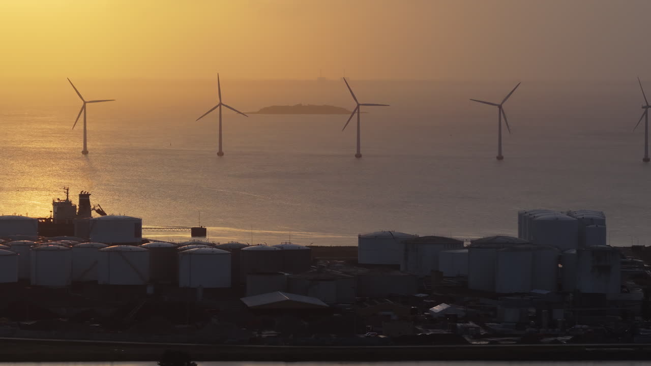 Aerial drone view of the golden sun over the Danish coast, casting light on offshore wind turbines
